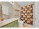 Cozy bathroom featuring a shower with floral curtain, a sink and a vanity, along with other essential fixtures at 12943 Lafayette St # F, Thornton, CO 80241