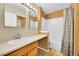 Cozy bathroom featuring a shower with patterned curtain, a sink and a vanity, and dual mirror setup at 12943 Lafayette St # F, Thornton, CO 80241