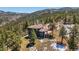 Aerial view of a well-maintained home surrounded by mature trees and nestled in a mountainous landscape at 290 Skyhill Dr, Evergreen, CO 80439