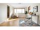 Bright bedroom boasts a large window, wood floors, a comfortable chair, and a sleek white desk at 7551 S Garland St, Littleton, CO 80128