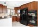 Well-equipped kitchen featuring dark wood cabinets, granite countertops, and modern black appliances at 7551 S Garland St, Littleton, CO 80128