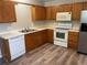 Functional kitchen with wood cabinets, white appliances, vinyl flooring, and stainless steel refrigerator at 18784 E Linvale Pl, Aurora, CO 80013