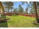 Spacious backyard featuring a red fence and mature trees at 30400 Hilltop Dr, Evergreen, CO 80439