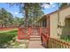 Charming home featuring a wooden deck with red railings, surrounded by green lawn and mature trees at 30400 Hilltop Dr, Evergreen, CO 80439