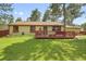 Charming home with a wooden deck and a spacious lawn, surrounded by beautiful mature trees at 30400 Hilltop Dr, Evergreen, CO 80439