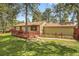 Exterior of a cozy home with a wooden deck, surrounded by lush greenery and mature trees at 30400 Hilltop Dr, Evergreen, CO 80439