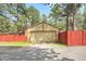Detached garage with a beige garage door and a red fence in the backyard at 30400 Hilltop Dr, Evergreen, CO 80439