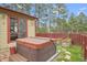 Backyard patio with a hot tub next to a sliding glass door and raised garden beds along a red fence at 30400 Hilltop Dr, Evergreen, CO 80439