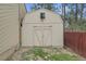 Beige shed with a window and double doors in the backyard of a house with a red fence at 30400 Hilltop Dr, Evergreen, CO 80439