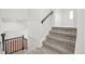 Carpeted stairs leading to the second floor, featuring a sleek black handrail at 8405 W 74Th Dr, Arvada, CO 80005