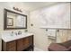 Well-lit bathroom with a wooden vanity, quartz countertop, decorative world map, and an accent chair at 6871 S Himalaya Way, Centennial, CO 80016