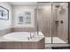 Bright bathroom featuring a soaking tub, a step-in shower with glass doors, and neutral-colored tile at 14565 Vancouver Pl, Parker, CO 80134