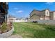 Large, grassy backyard with a stone retaining wall and white fence, offering ample space at 6454 Leathers Ln, Parker, CO 80134