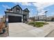 Modern two-story home with a spacious driveway, gray siding, black trim and a well-manicured lawn at 6454 Leathers Ln, Parker, CO 80134