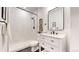 Bathroom with a modern vanity, sleek black hardware, white marble walls, and walk in shower at 7932 E 49Th Pl, Denver, CO 80238