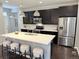 Modern kitchen with stainless steel appliances, dark cabinets, a center island, and stylish pendant lighting at 7932 E 49Th Pl, Denver, CO 80238