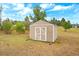 Outdoor storage shed with double doors in a grassy yard surrounded by greenery under a blue sky at 3639 Pine Meadow Ave, Parker, CO 80138
