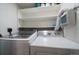 Well-lit laundry room featuring modern washer and dryer with overhead shelving at 12143 Melody Dr # 103, Denver, CO 80234