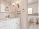 This bathroom includes a tub/shower combo, tile backsplash, white vanity, gold fixtures and pink walls at 1350 Valentia St, Denver, CO 80220