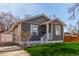 Cozy home featuring gray siding, a bright blue door, detached garage, and well-kept lawn at 1350 Valentia St, Denver, CO 80220