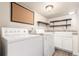 Well-equipped laundry room with modern washer and dryer, storage shelves, and tiled floor at 1350 Valentia St, Denver, CO 80220