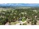 Aerial view of the property showcasing the home surrounded by a lush forest and distant mountain views at 33589 Robin Ct, Elizabeth, CO 80107