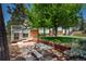 Backyard featuring a stone patio with picnic table, mature trees, and landscaping at 33589 Robin Ct, Elizabeth, CO 80107