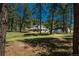 Scenic property featuring lush greenery, towering pine trees, and a charming white home nestled amongst the landscape at 33589 Robin Ct, Elizabeth, CO 80107