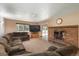 Cozy living room with a brick fireplace, large sectional sofa, and views of the backyard at 33589 Robin Ct, Elizabeth, CO 80107