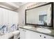 Bright bathroom features a double sink vanity, full mirror, and shower with decorative blue curtain at 1271 Braewood Ave, Highlands Ranch, CO 80129
