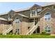 Inviting exterior of a multi-story condo building featuring stone accents, stairs, and manicured lawn at 3261 S Waco Ct # K, Aurora, CO 80013