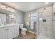 Bathroom featuring walk-in shower with glass door and marbled tiling, toilet, wood floor and white sink at 9510 Flower St, Broomfield, CO 80021