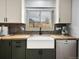 Farmhouse sink situated between cabinetry and stainless steel dishwasher under a window allowing natural light at 9510 Flower St, Broomfield, CO 80021