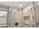 Close-up of a shower featuring chrome hardware, marble tiling, window and built-in shelves at 9510 Flower St, Broomfield, CO 80021