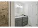 Updated bathroom with gray vanity, oval mirror, and tiled shower with assist bar at 3596 E Fair Pl, Centennial, CO 80121