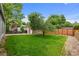 Spacious green backyard with a tree, a detached brick garage, and patio seating at 1429 Hudson St, Denver, CO 80220