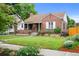 Brick home featuring a cozy front porch, manicured lawn, and vibrant garden beds, enhancing its curb appeal at 1429 Hudson St, Denver, CO 80220