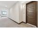 Carpeted hallway leading to unit entrance with brown front door at 485 Interlocken Blvd # 201, Broomfield, CO 80021