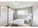 Stylish bedroom featuring an sliding barn door, plush bed, soft lighting, and natural light from large window at 9141 Gail Ct, Thornton, CO 80229
