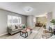 Bright living room showcases modern design, gray sofa, wood floors, and open flow to dining space at 9141 Gail Ct, Thornton, CO 80229