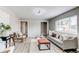 Comfortable living room features gray sofa, light-toned wood floors, and abundant natural light from large window at 9141 Gail Ct, Thornton, CO 80229