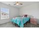 Bright bedroom featuring a twin bed with a blue comforter, a ceiling fan, and a window at 9031 Apache Plume Dr # E, Parker, CO 80134