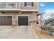 Exterior view of townhome showing a two car garage, stone accents, and well-kept landscaping at 9031 Apache Plume Dr # E, Parker, CO 80134