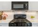 Close up of stove with black appliances, white cabinets and subway tile backsplash at 9031 Apache Plume Dr # E, Parker, CO 80134