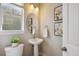 This bathroom features a pedestal sink, an oval mirror, and artwork enhancing the clean, simple design at 10671 E 28Th Ave, Denver, CO 80238