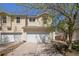 A charming townhouse with a two-car garage and light-yellow siding, with a beautiful tree and blue skies at 817 Pintail Ave, Brighton, CO 80601