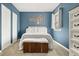 Bedroom with a white bed, a wooden chest, and tree-inspired wall decor, lit by a bright window at 1920 Ulster St, Denver, CO 80220