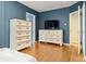Spacious main bedroom with hardwood floors, white dressers, and a television set at 1920 Ulster St, Denver, CO 80220