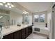Bright bathroom featuring double sinks, a soaking tub under a window, and a glass-enclosed shower at 15432 Greenstone Cir, Parker, CO 80134