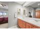 Bathroom with double sinks, wood cabinets and a view into the bedroom at 43097 Taos Trl, Elizabeth, CO 80107